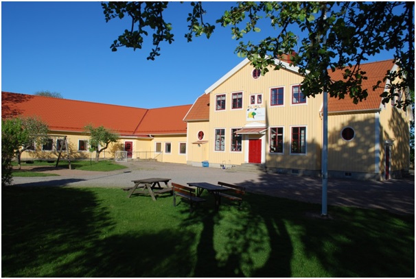 En gul byggnad med röd dörr och tegeltag.
