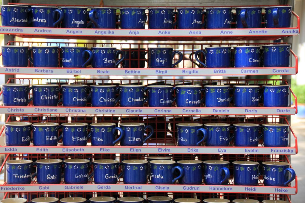 många blåa muggar med olika namn på.