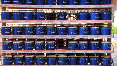 många blåa muggar med olika namn på.