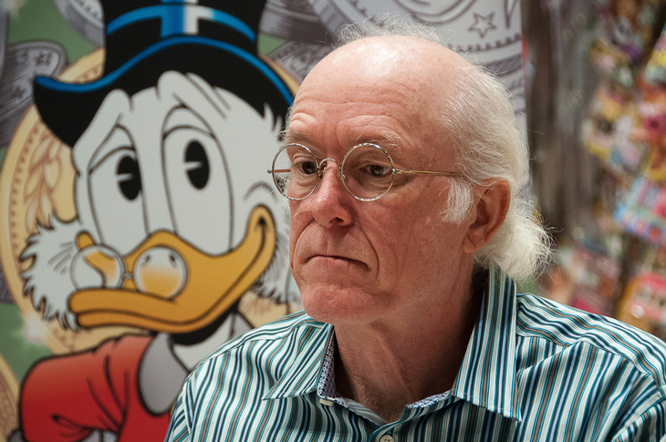 Tecknaren Don Rosa sitter framför en bild av Joakim von Anka
