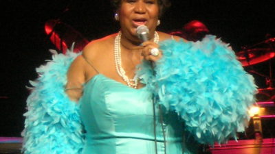 Aretha Franklin i en turkod klänning på scen.