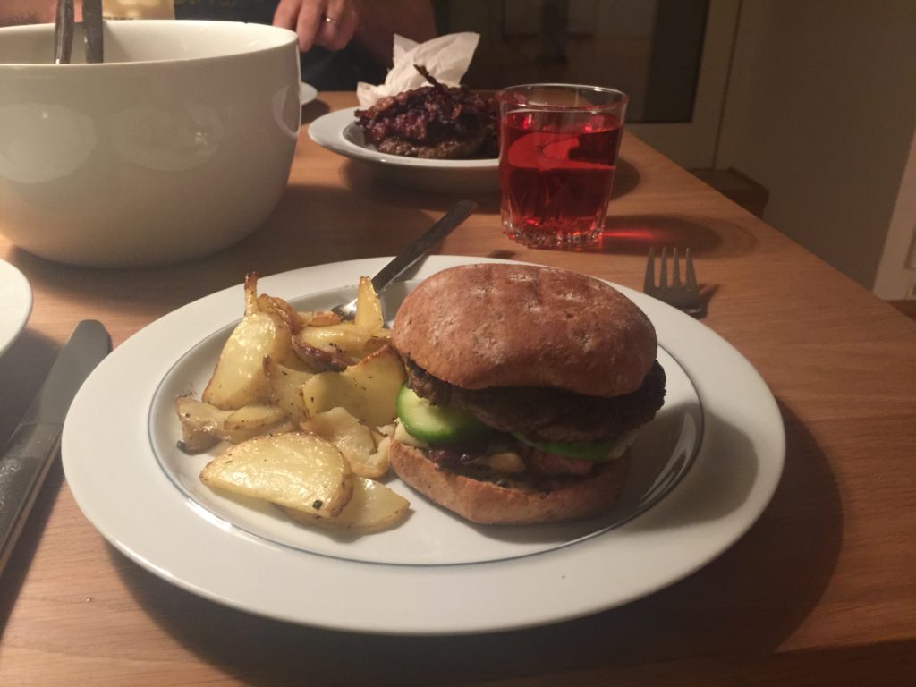 En hamburgare med klyftpotatis bredvis.
