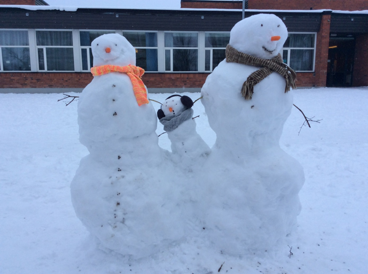 Tre snögubbar utanför en skola