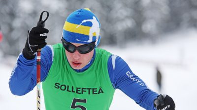 Zebastian Modin kämpar på sina skidor. Han har ett par svarta, mörkläggande glasögon för att alla ska tävla på samma villkor.