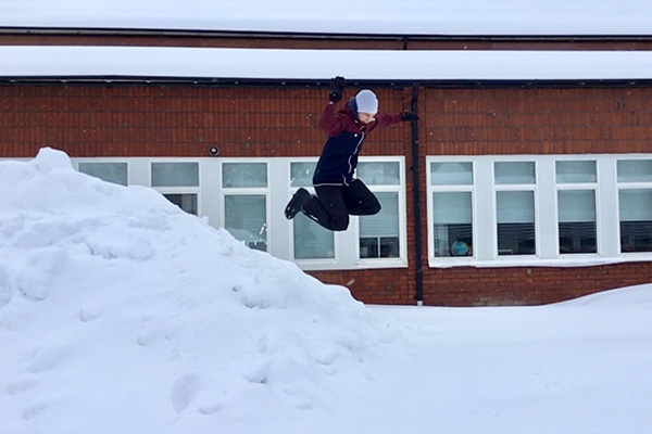 Foto på elev som hoppar i snöhög.