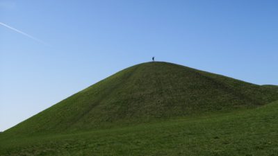 Liten människa högst uppe på grön kulle