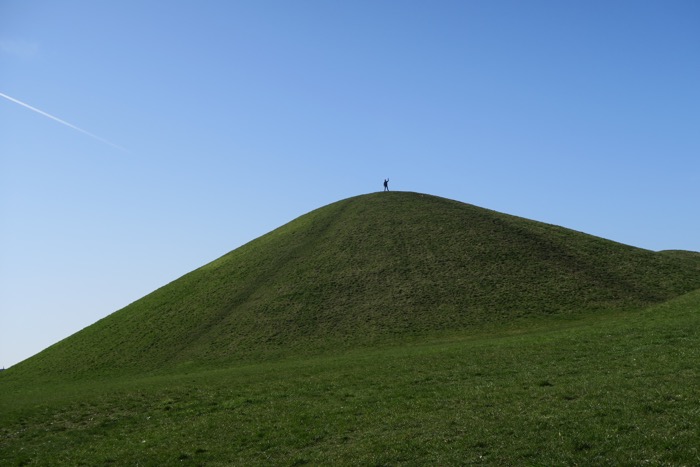 Liten människa högst uppe på grön kulle