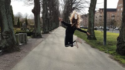 Tjej hopparpå en väg på en kyrkogård