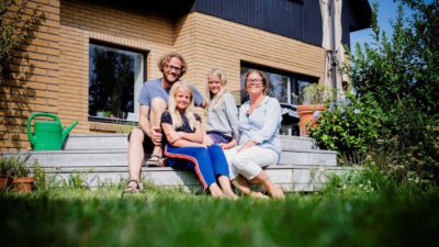 Skånsk familj sitter framför sitt hus