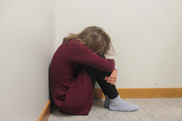 Foto på elev som gömmer ansiktet i knät.