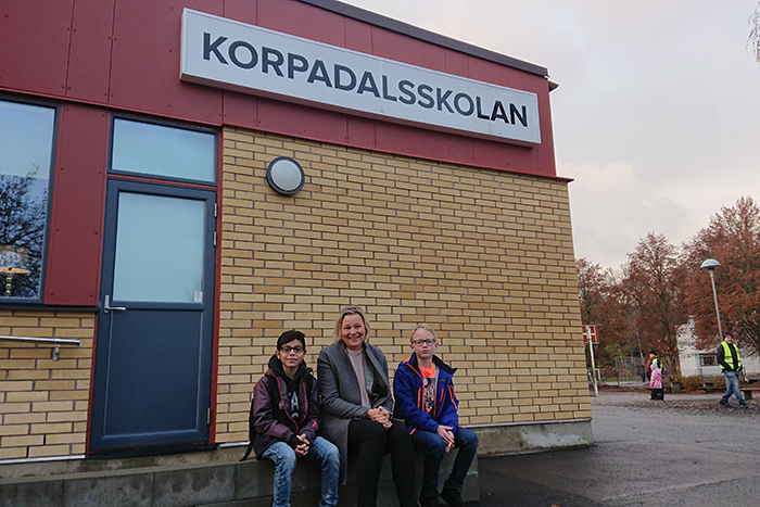 Annica, Mumen och Noah sitter på en bänk vid Korpadalsskolan.