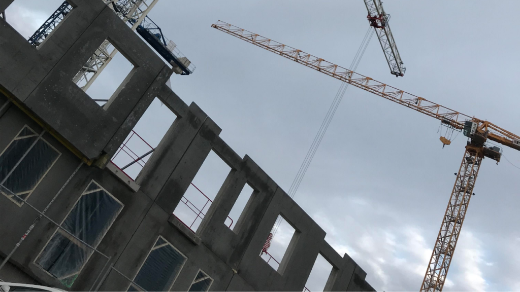 En byggkran bakom ett hus som byggs.