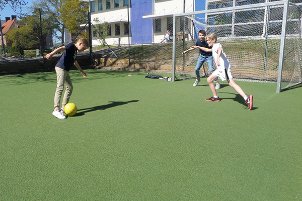 Tre elever som spelar fotboll.
