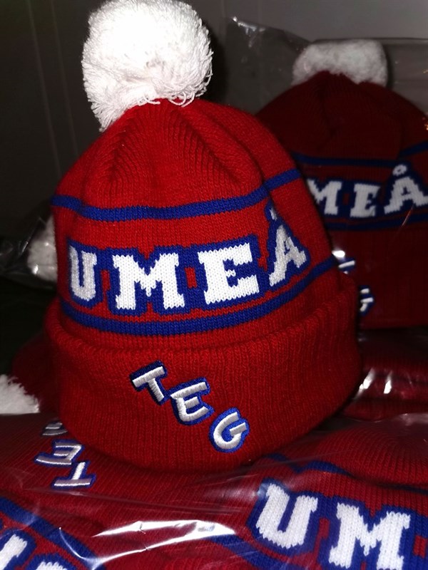 Röda mössor som det står Umeå och Teg på.