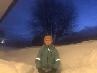 En elev står framför en snöhög.