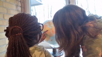 Maeva och Munise som tittar och pekar på en jordglob.