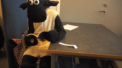 Fåret Shaun sitter och läser.